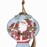 Hand-painted glass ornament featuring Santa holding stockings filled with gifts, surrounded by festive holly in a snowy scene.