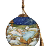 Glass ornament depicting baby Jesus sleeping in a manger, surrounded by lambs under a glowing star in a peaceful nativity scene.
