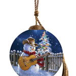 Hand-painted glass ornament featuring a cowboy snowman with a guitar under a starry Christmas night.
