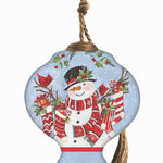 Hand-painted glass ornament featuring Santa holding stockings filled with gifts, surrounded by festive holly in a snowy scene.