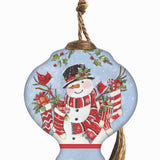 Hand-painted glass ornament featuring Santa holding stockings filled with gifts, surrounded by festive holly in a snowy scene.