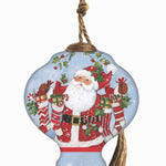 Hand-painted glass ornament featuring Santa holding stockings filled with gifts, surrounded by festive holly in a snowy scene.
